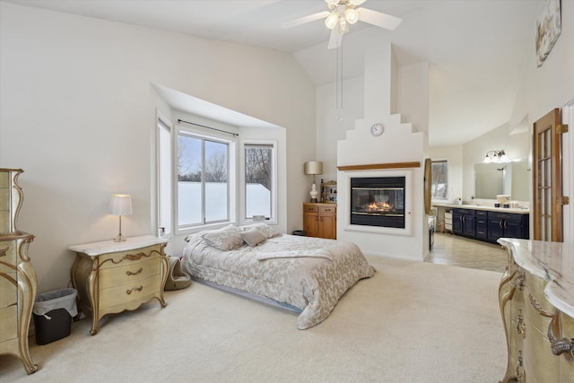 carpeted bedroom with ceiling fan, lofted ceiling, and ensuite bathroom