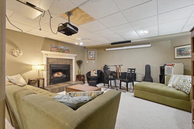 carpeted living room featuring a tile fireplace and a drop ceiling