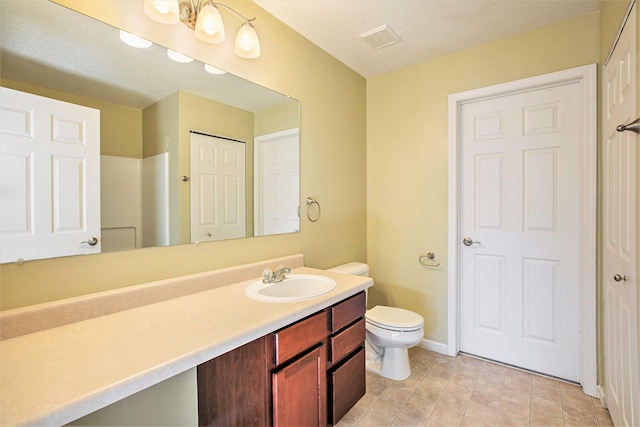 bathroom with a textured ceiling, vanity, and toilet