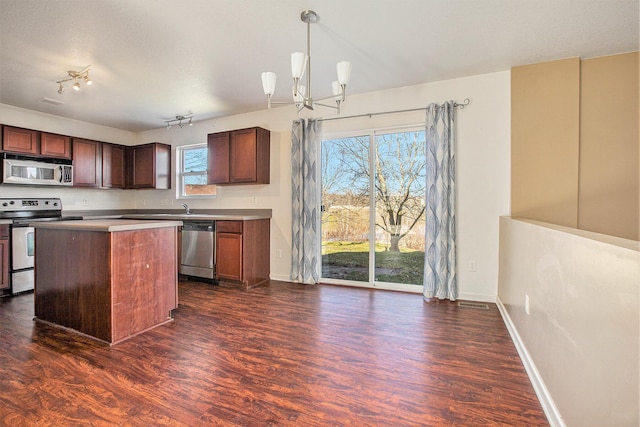 kitchen with a center island, dark wood-type flooring, hanging light fixtures, stainless steel appliances, and a chandelier