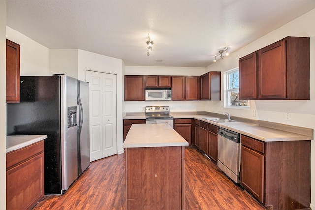 kitchen with appliances with stainless steel finishes, a textured ceiling, dark wood-type flooring, sink, and a kitchen island