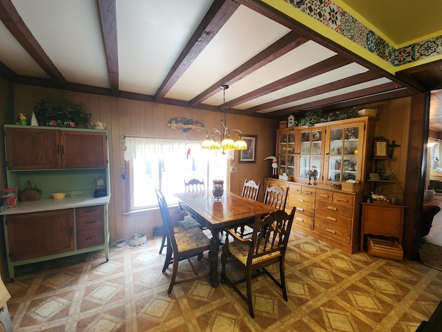 dining area featuring a chandelier, beam ceiling, light parquet flooring, and wooden walls