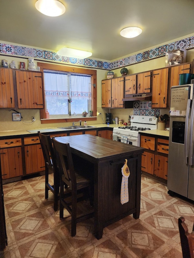 kitchen with sink, white gas range oven, stainless steel refrigerator with ice dispenser, tasteful backsplash, and a kitchen island