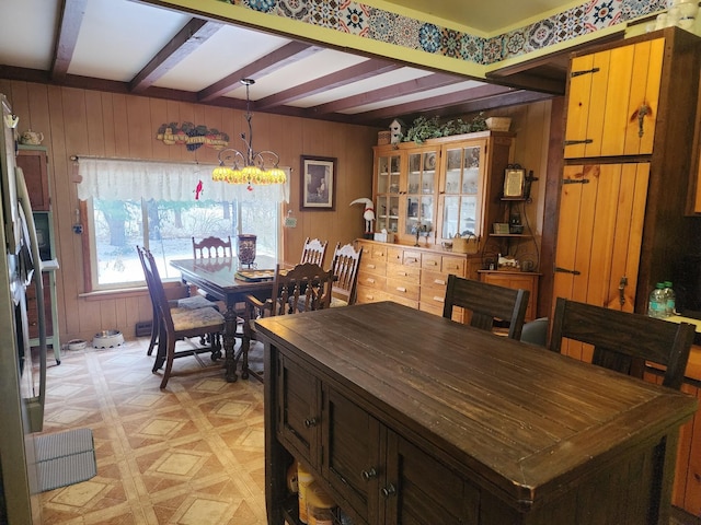 dining space featuring beam ceiling, wood walls, light parquet flooring, and a notable chandelier