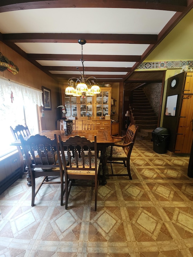 dining space featuring wood walls, beamed ceiling, and a notable chandelier