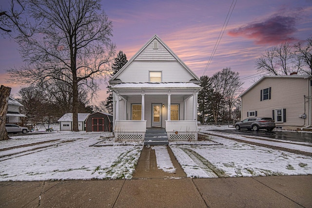 bungalow-style house featuring a porch and a shed