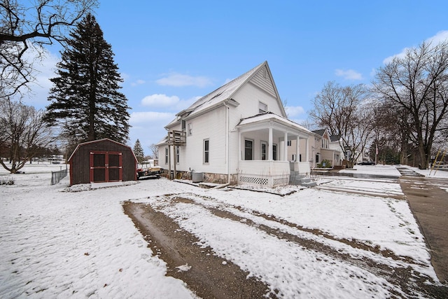 snow covered property with a shed and cooling unit