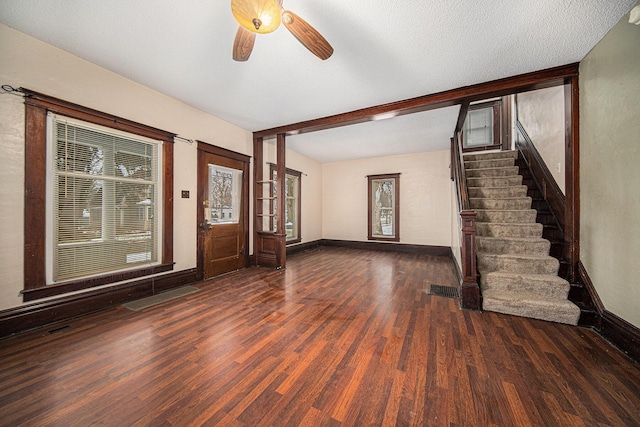 interior space featuring beamed ceiling, a textured ceiling, ceiling fan, and dark wood-type flooring