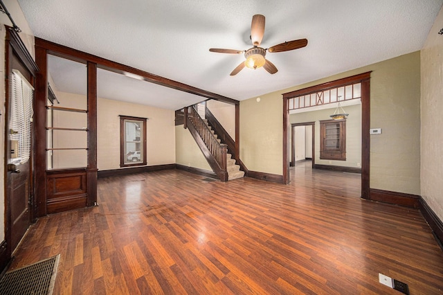 unfurnished room with a textured ceiling, ceiling fan, and dark wood-type flooring