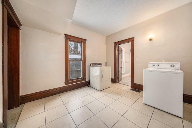 washroom with washer and clothes dryer, light tile patterned floors, and a textured ceiling