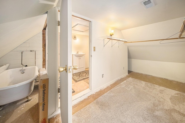 bathroom featuring a tub to relax in and lofted ceiling