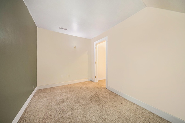 spare room with light colored carpet and lofted ceiling