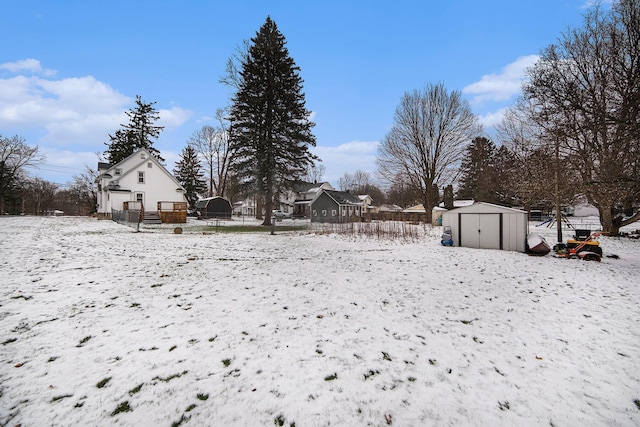 yard covered in snow featuring a deck and a storage shed