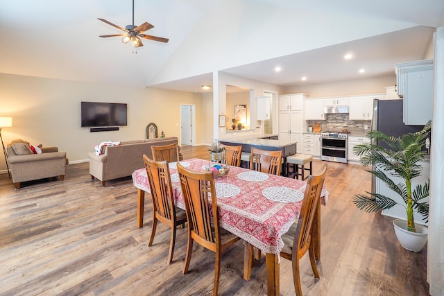 dining area featuring ceiling fan, high vaulted ceiling, and light hardwood / wood-style floors