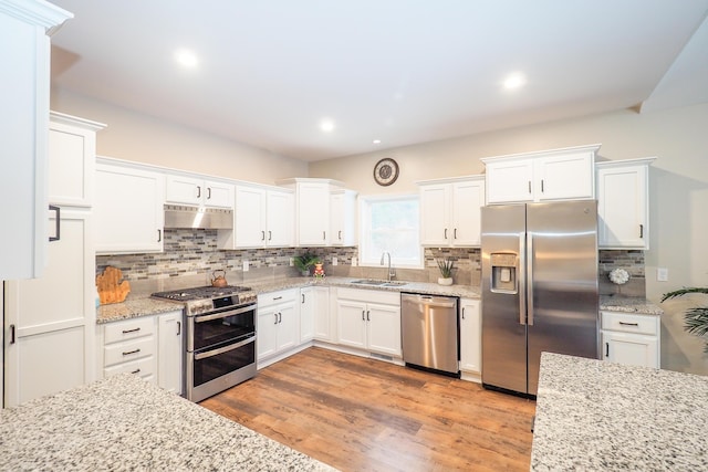 kitchen with white cabinetry, sink, stainless steel appliances, light stone counters, and light wood-type flooring