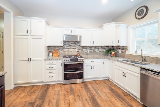 kitchen featuring white cabinetry, sink, stainless steel appliances, and light stone counters