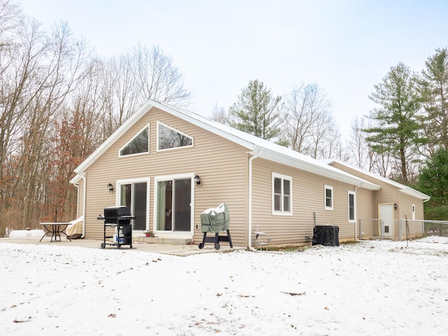 snow covered rear of property with a patio