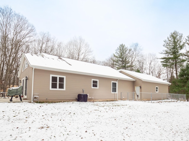 snow covered back of property featuring central AC unit