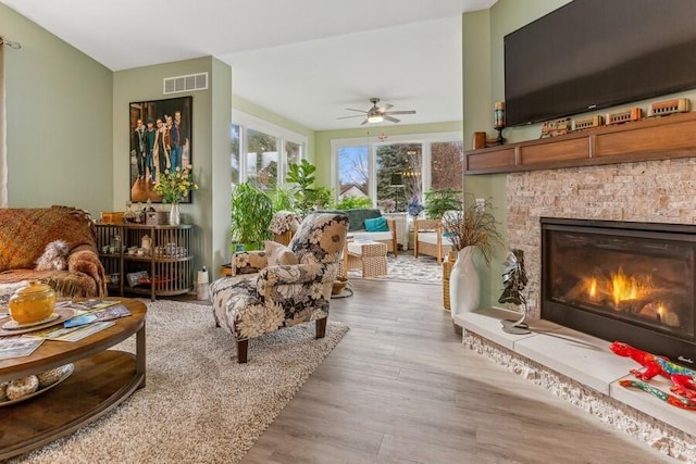 interior space featuring a fireplace, ceiling fan, and light hardwood / wood-style flooring