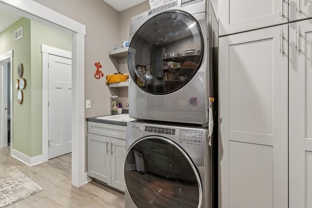 laundry room featuring stacked washer and dryer and cabinets