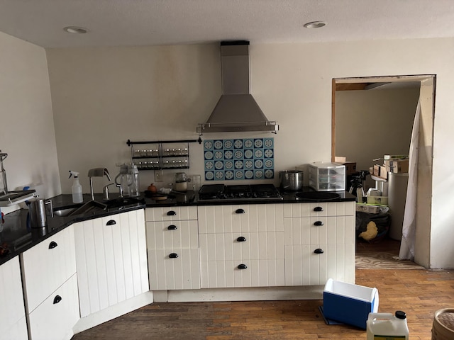 kitchen featuring white cabinetry, hardwood / wood-style flooring, and wall chimney range hood