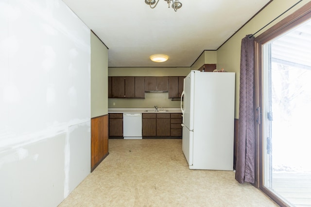 kitchen with a wealth of natural light, dark brown cabinets, white appliances, and sink