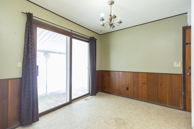 carpeted spare room with an inviting chandelier