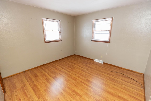 unfurnished room featuring light hardwood / wood-style floors and plenty of natural light