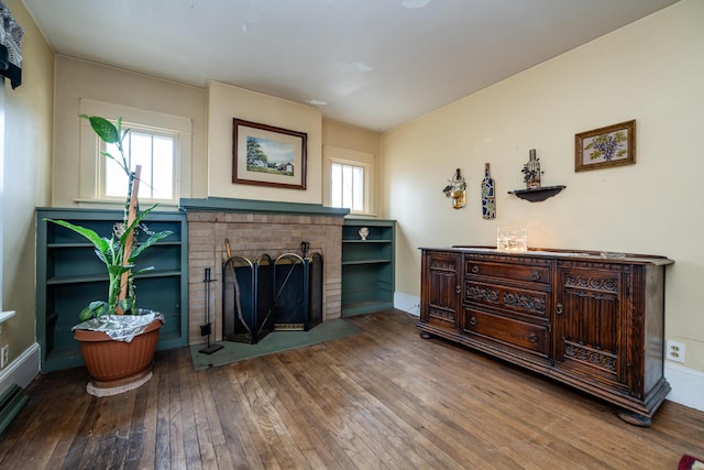 sitting room with hardwood / wood-style flooring and a brick fireplace