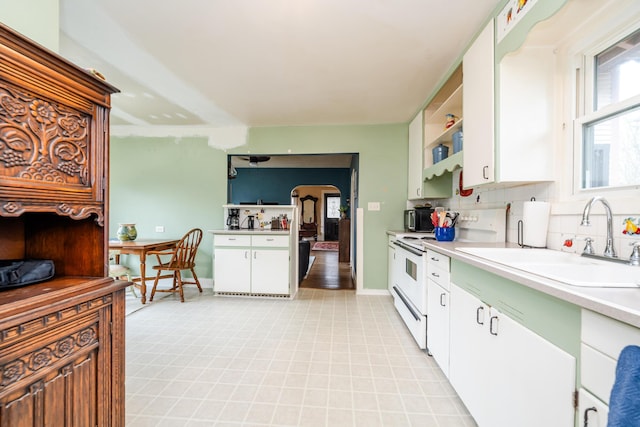 kitchen featuring backsplash, white electric range, white cabinetry, and sink