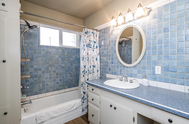 bathroom featuring hardwood / wood-style floors, shower / bath combo, vanity, decorative backsplash, and tile walls