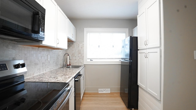 kitchen featuring white cabinetry, sink, light stone counters, and black appliances