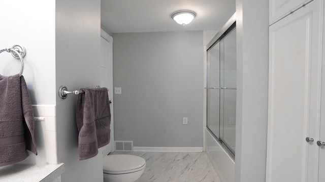 bathroom with enclosed tub / shower combo and toilet