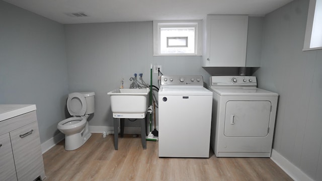 laundry room featuring washer and clothes dryer, sink, and light hardwood / wood-style flooring