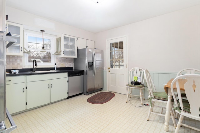 kitchen featuring backsplash, white cabinets, sink, appliances with stainless steel finishes, and decorative light fixtures