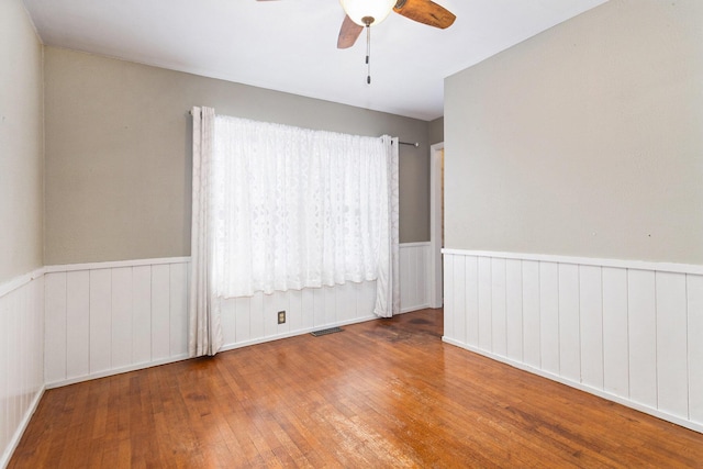 empty room featuring wood-type flooring, ceiling fan, and a healthy amount of sunlight