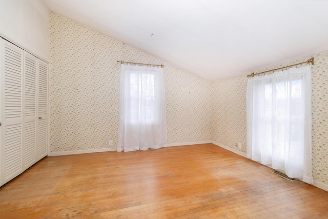 unfurnished bedroom featuring a closet, vaulted ceiling, and light hardwood / wood-style flooring