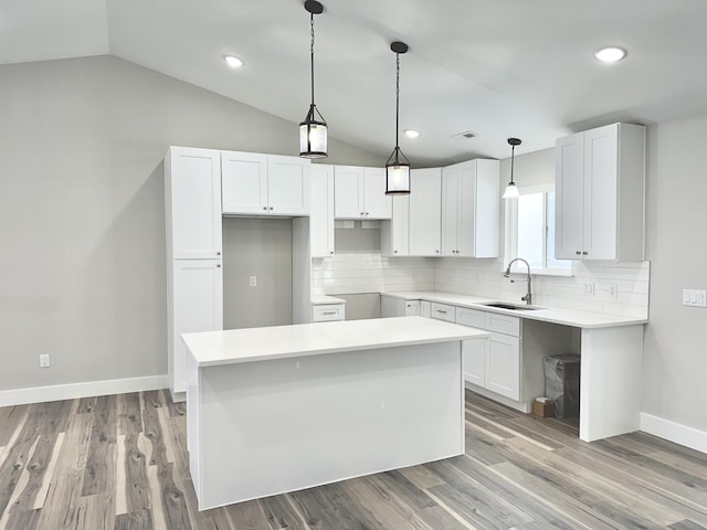 kitchen with white cabinets, a center island, lofted ceiling, and sink