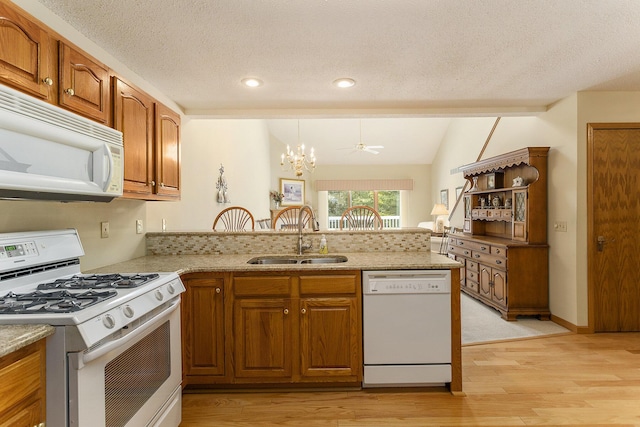 kitchen featuring sink, kitchen peninsula, light hardwood / wood-style floors, white appliances, and ceiling fan with notable chandelier