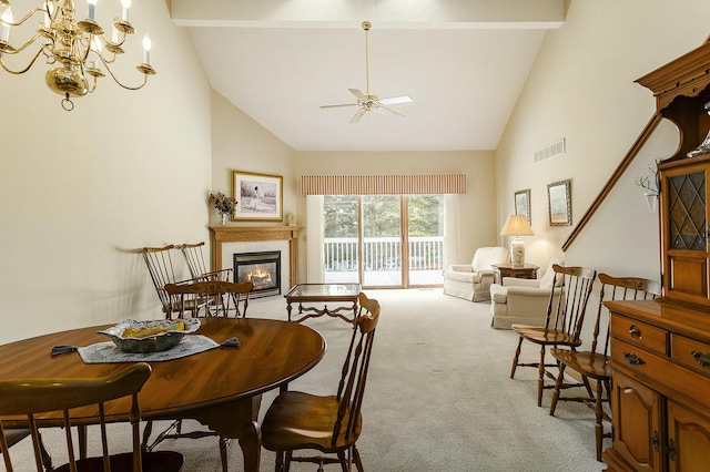 carpeted dining space featuring high vaulted ceiling, beam ceiling, ceiling fan with notable chandelier, and a tile fireplace