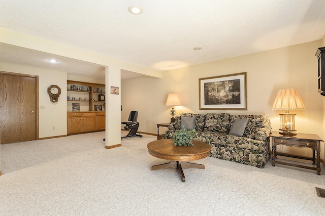 living room with carpet flooring, built in shelves, and a textured ceiling