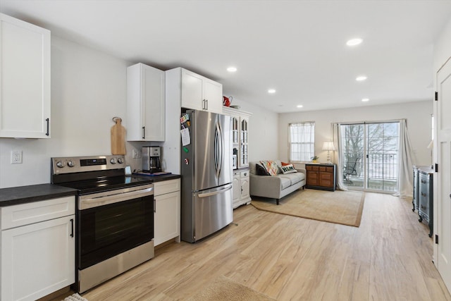 kitchen with stainless steel appliances, white cabinets, and light hardwood / wood-style flooring