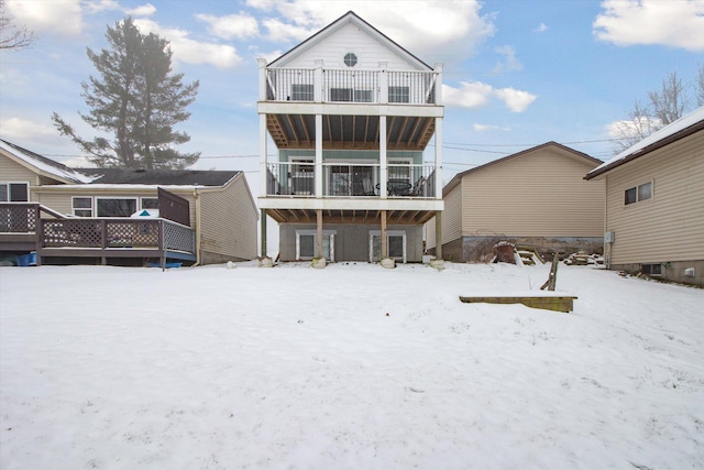 snow covered back of property with a balcony