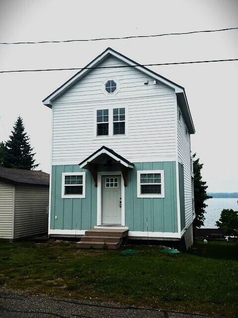 10606 Lake St, Chippewa Lake, MI 49320 - view of front facade with board and batten siding and a front lawn