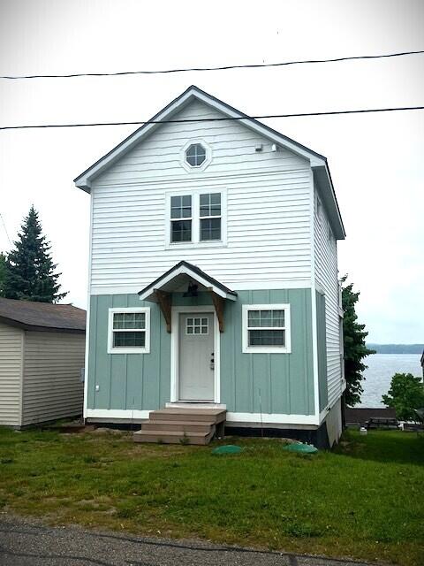 10606 Lake St, Chippewa Lake, MI 49320 - view of front of home with board and batten siding, a front yard, and a water view