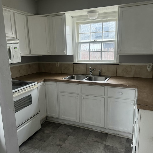 kitchen with decorative backsplash, stove, white cabinetry, and sink