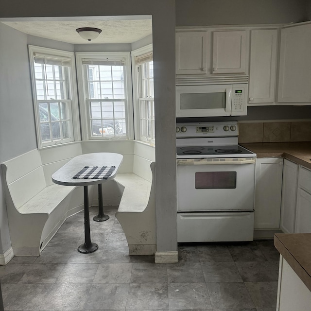 kitchen with white cabinets, white appliances, and a healthy amount of sunlight