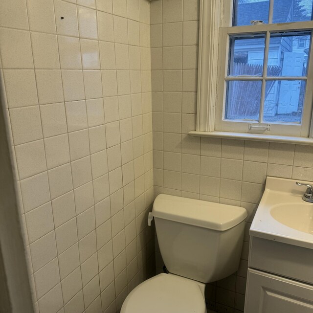 bathroom with vanity, tile walls, and toilet