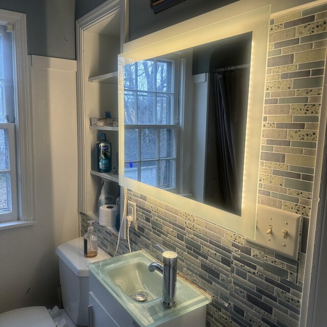 bathroom with vanity, tasteful backsplash, toilet, and a wealth of natural light