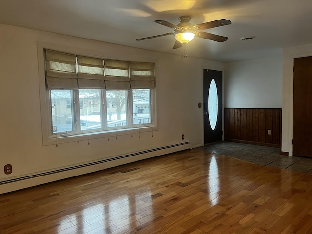 entrance foyer featuring hardwood / wood-style floors, baseboard heating, wood walls, and ceiling fan